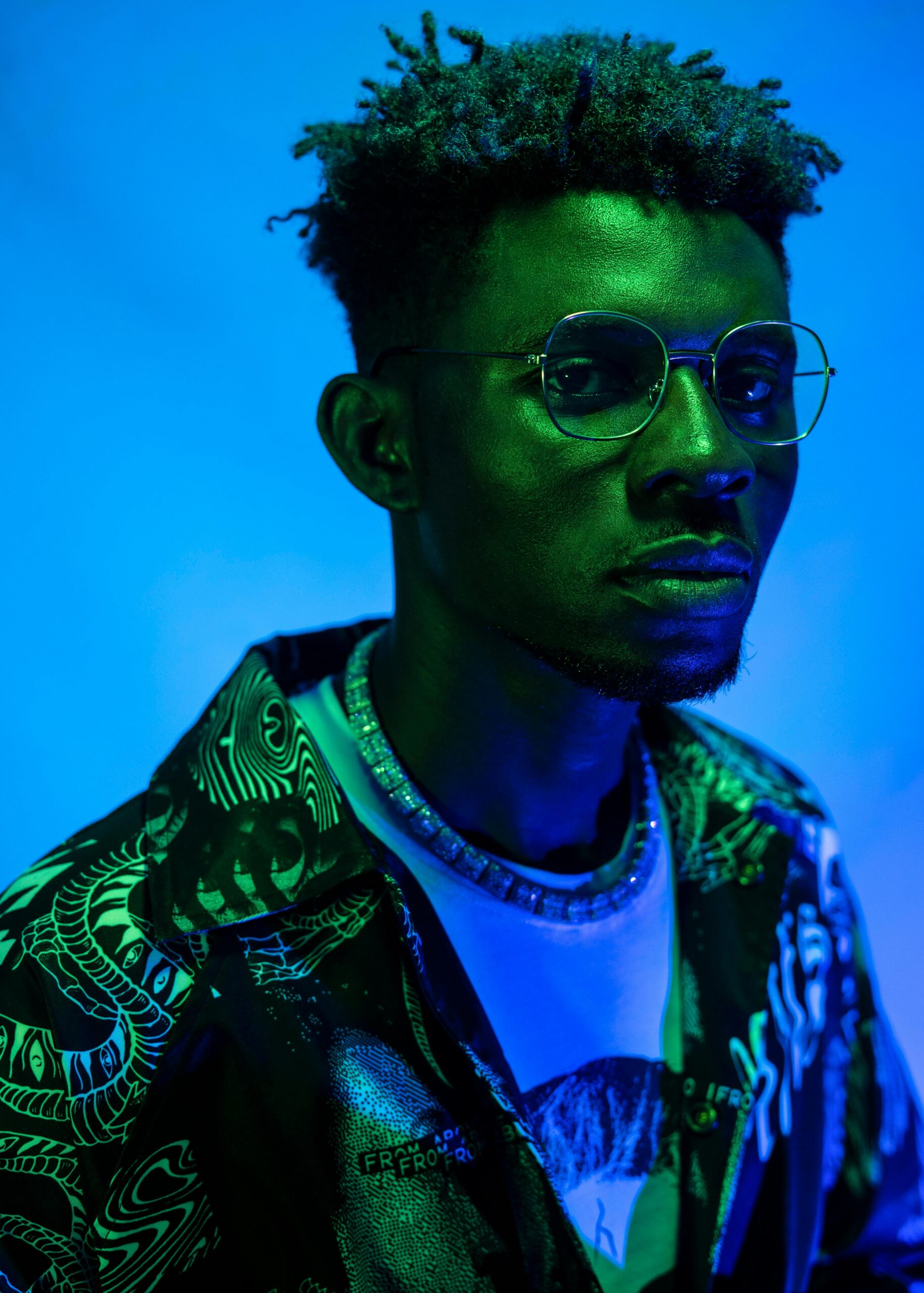 Home Striking portrait of a man with glasses and unique style in neon lighting.